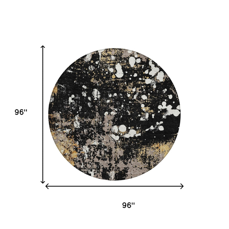 Round abstract area rug, black base with white splatters and gold flecks, flat top view