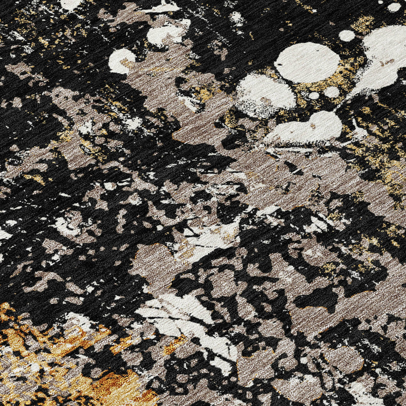 Close-up texture of round abstract area rug with black, white, and gold speckled pattern