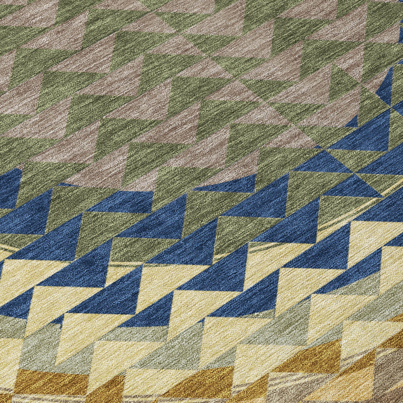 Geometric chevron rug close-up with olive, blue, and cream blocks and speckled texture.