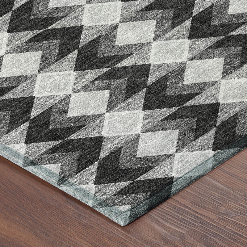 Corner of black, gray, and white geometric rug on wood floor, diamond pattern
