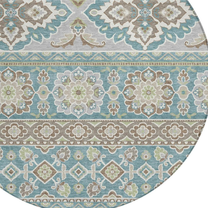 Close-up of round area rug border with teal stripes and tan, blue, and green florals