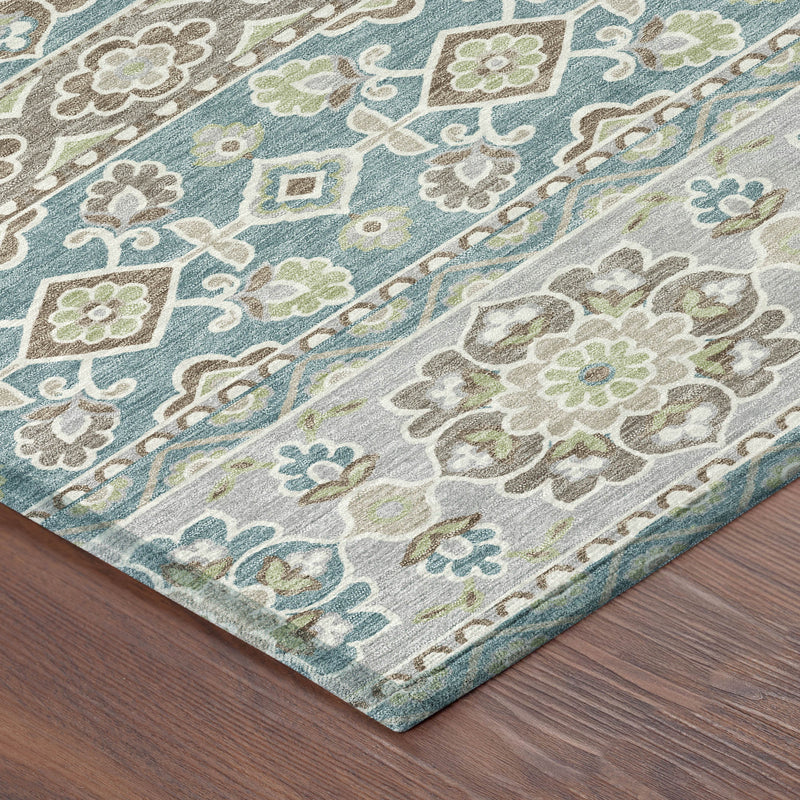 Corner detail of teal and green patterned area rug with scrolling floral motifs