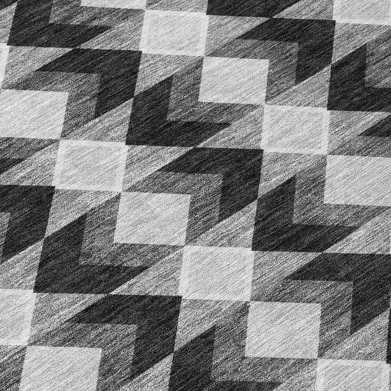 Geometric area rug detail showing black, gray, and white woven-look square blocks.