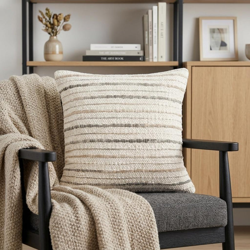 Cream and beige striped throw pillow cover on a chair with textured bands