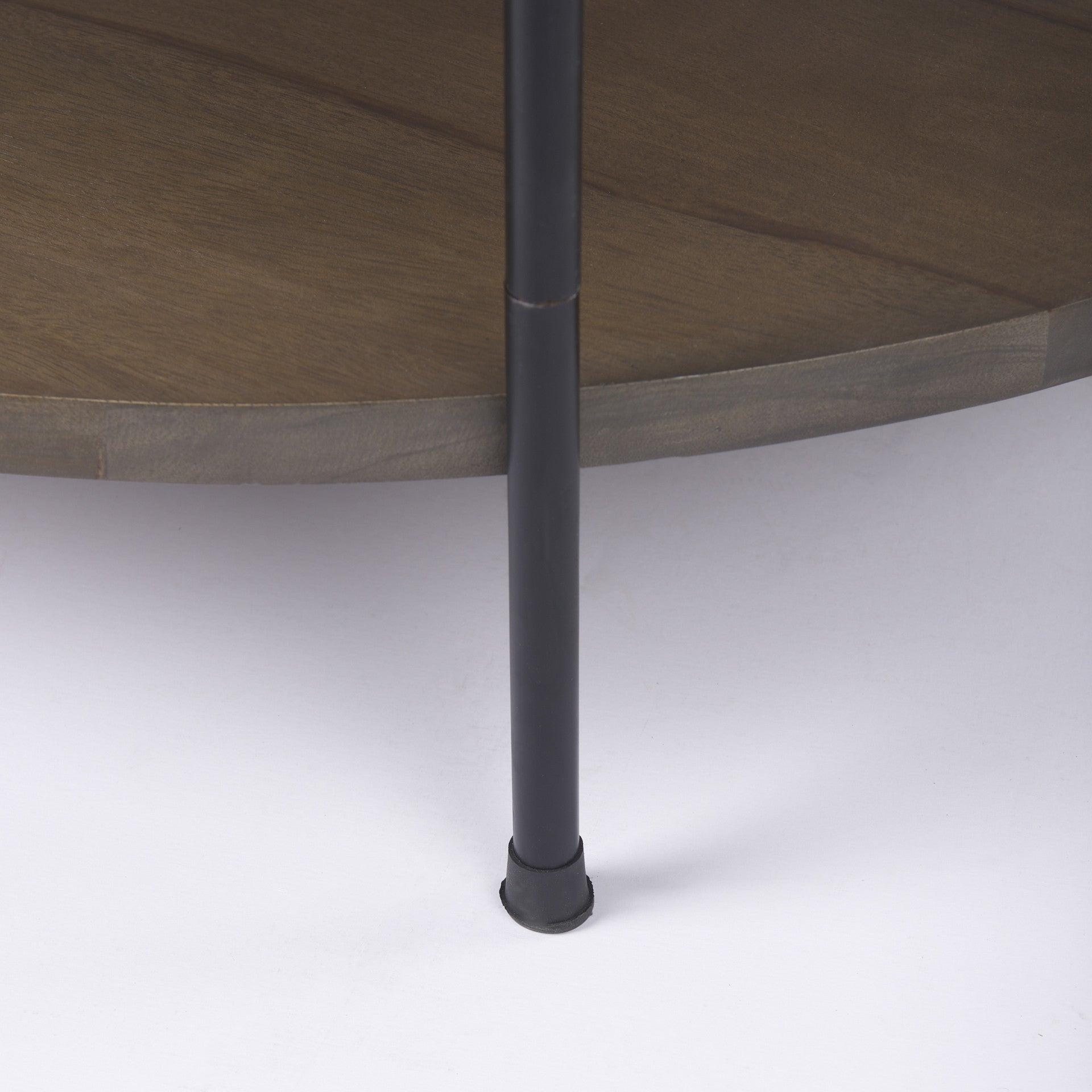 Round coffee table: black iron leg with circular base on white floor, dark wood apron