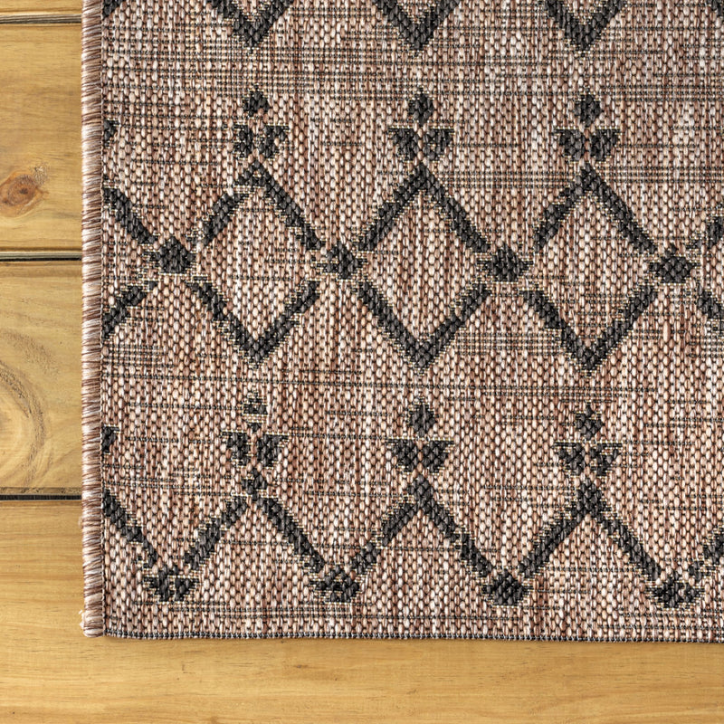 Beige indoor-outdoor rug with black diamond trellis and stitched border edging