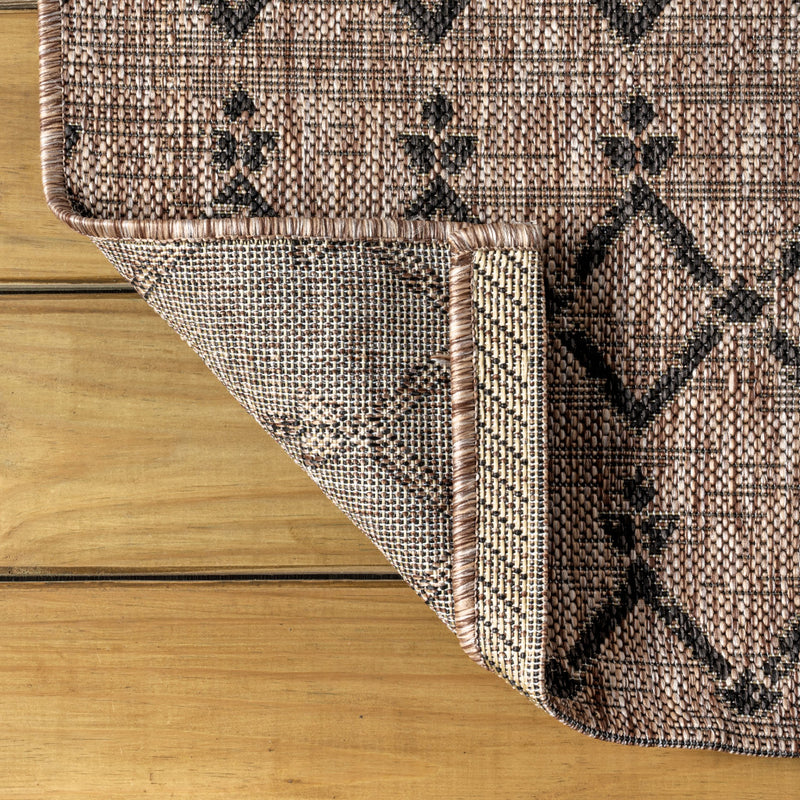 Indoor-outdoor area rug with black diamond trellis pattern and beige woven texture