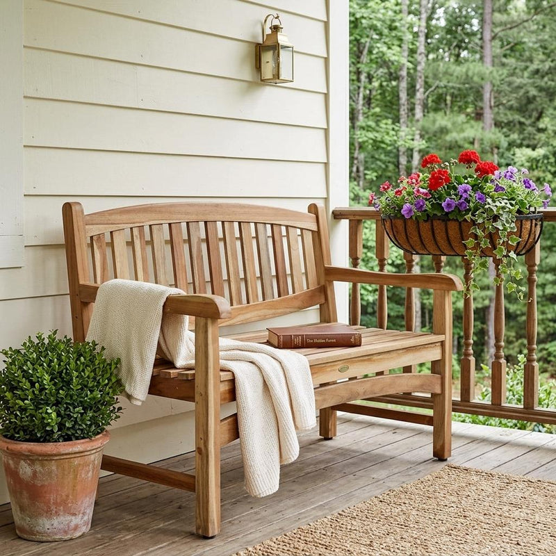 Teak outdoor bench with slatted back and armrests, beige cushion and throw