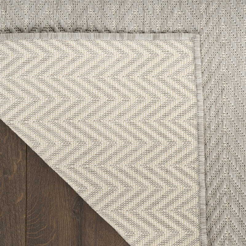 Light gray area rug corner with textured chevron zigzag pattern