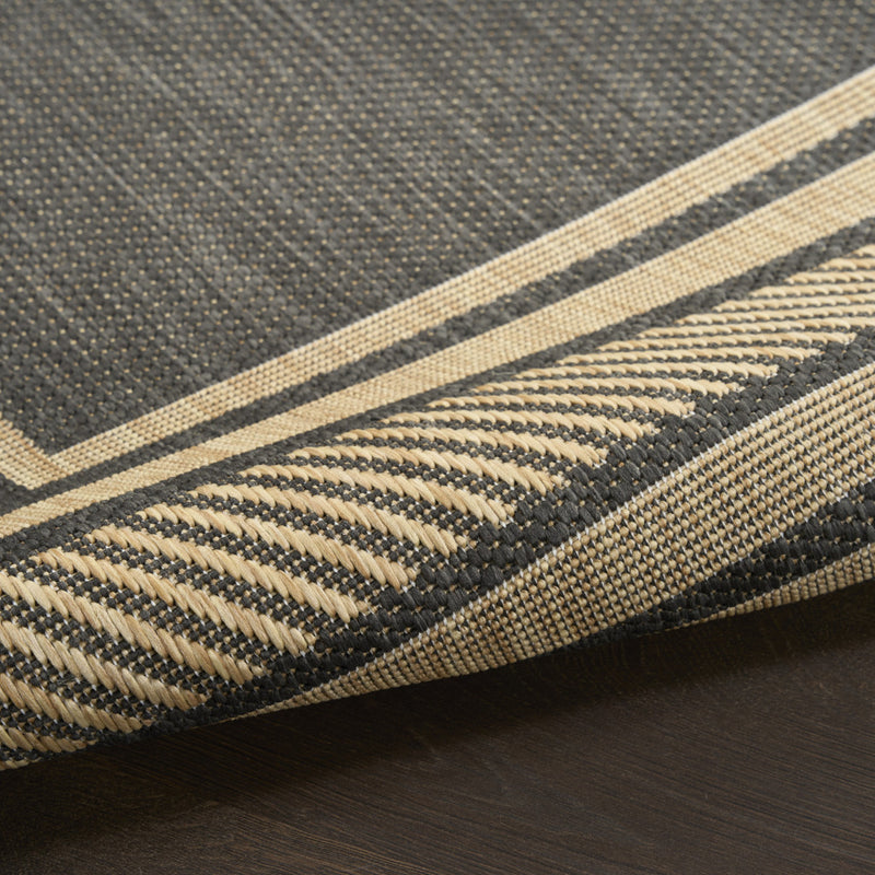 Close-up of charcoal woven area rug texture with beige border stripes