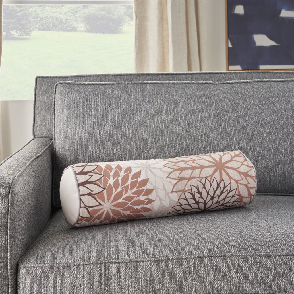 Floral bolster throw pillow on a sofa; beige fabric with brown and ivory flower print.