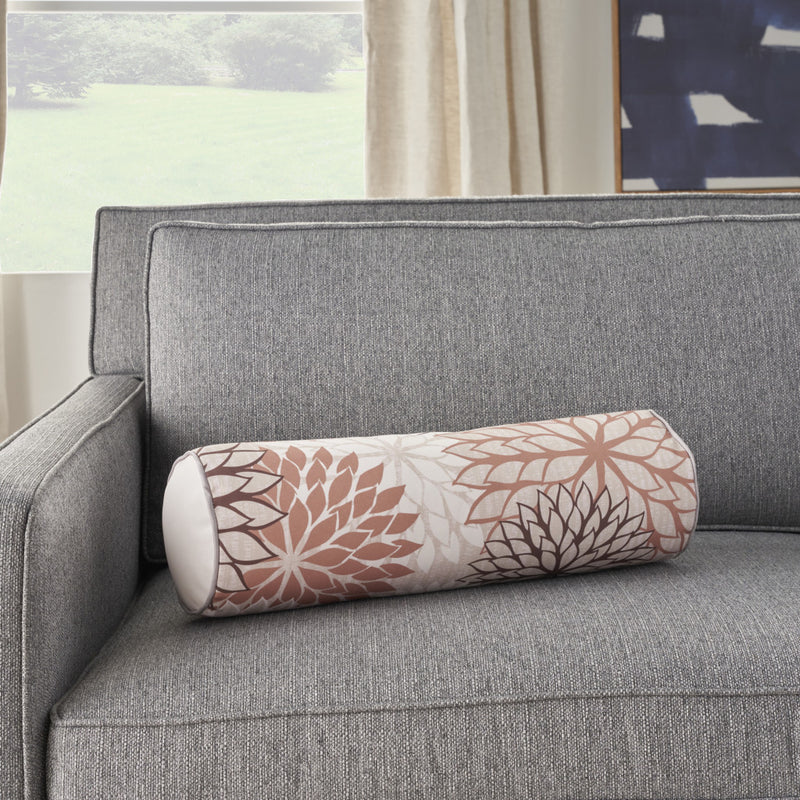 Floral bolster throw pillow on a sofa; beige fabric with brown and ivory flower print.