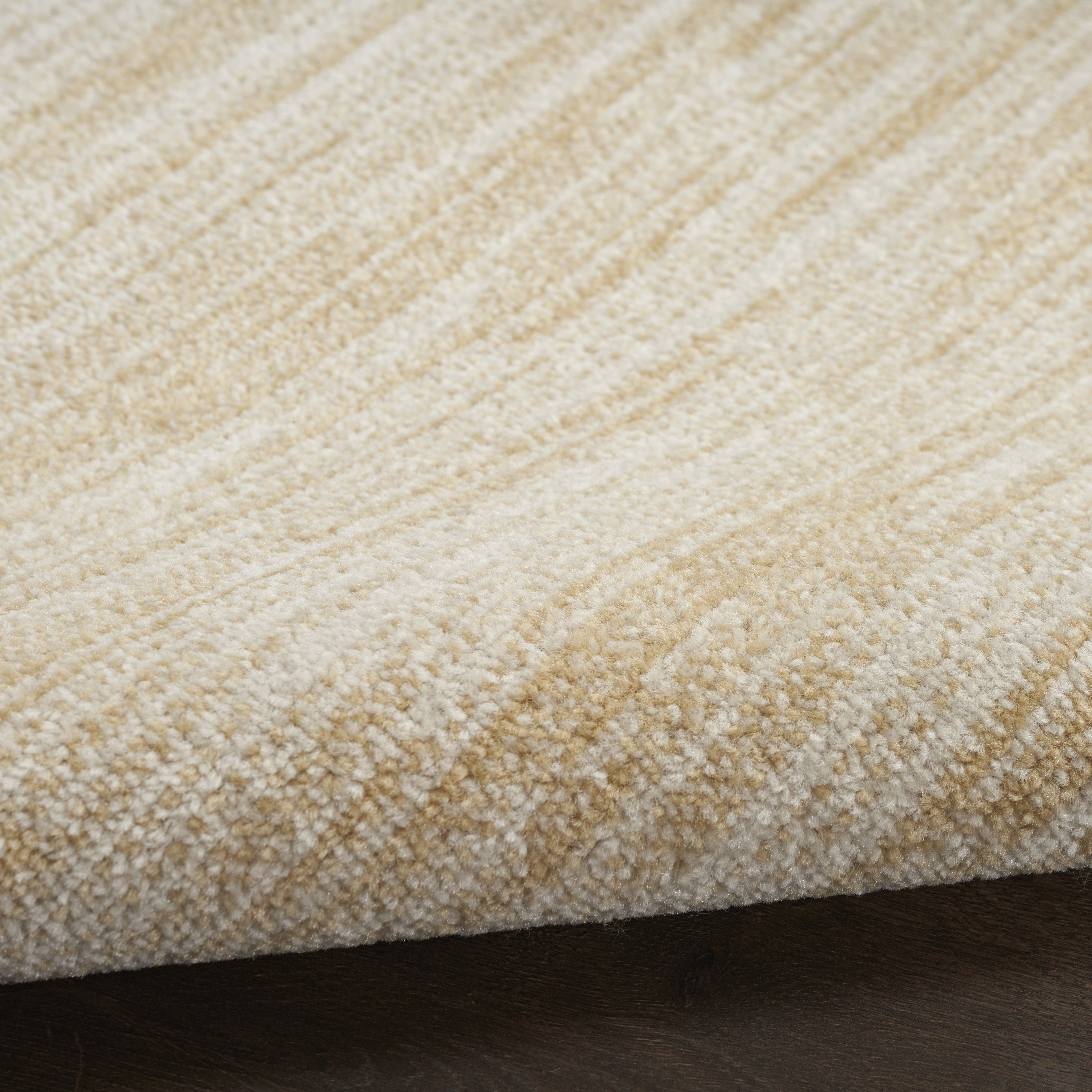 Ivory rug pile with gold-toned horizontal streaks, tight close-up