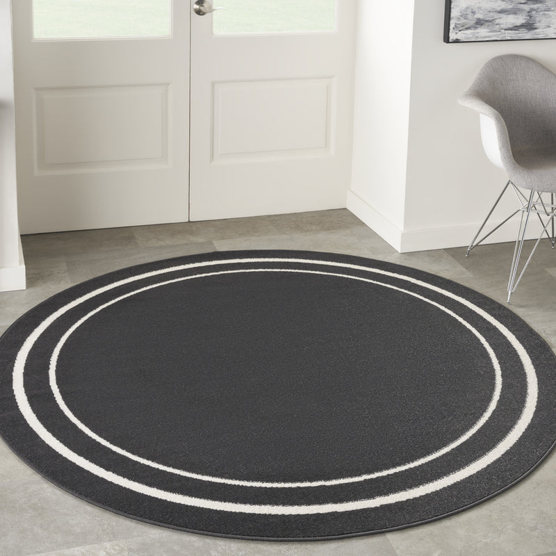 Round black area rug with ivory concentric circle stripes, full round view