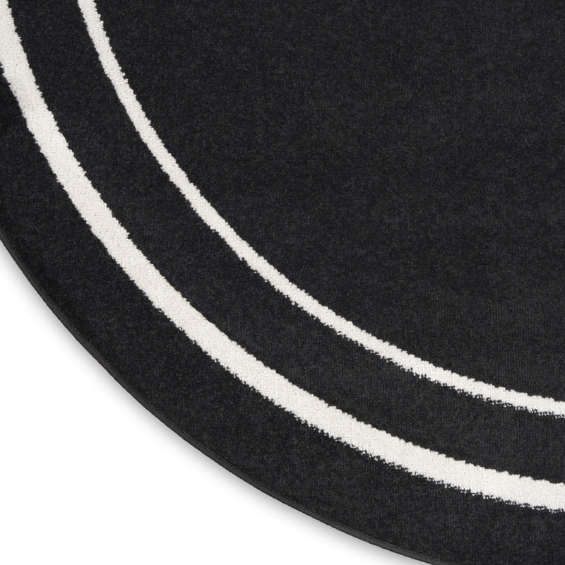 Round black rug detail: ivory double stripe bands on textured pile, curved perimeter