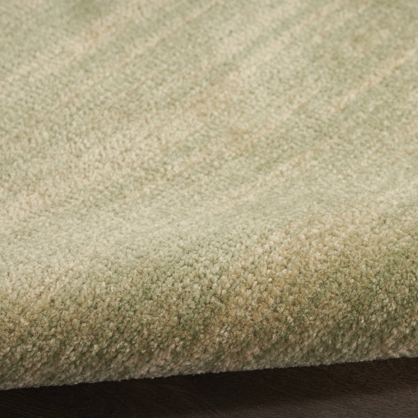 Green and gold abstract area rug with dense short pile texture, close-up surface view