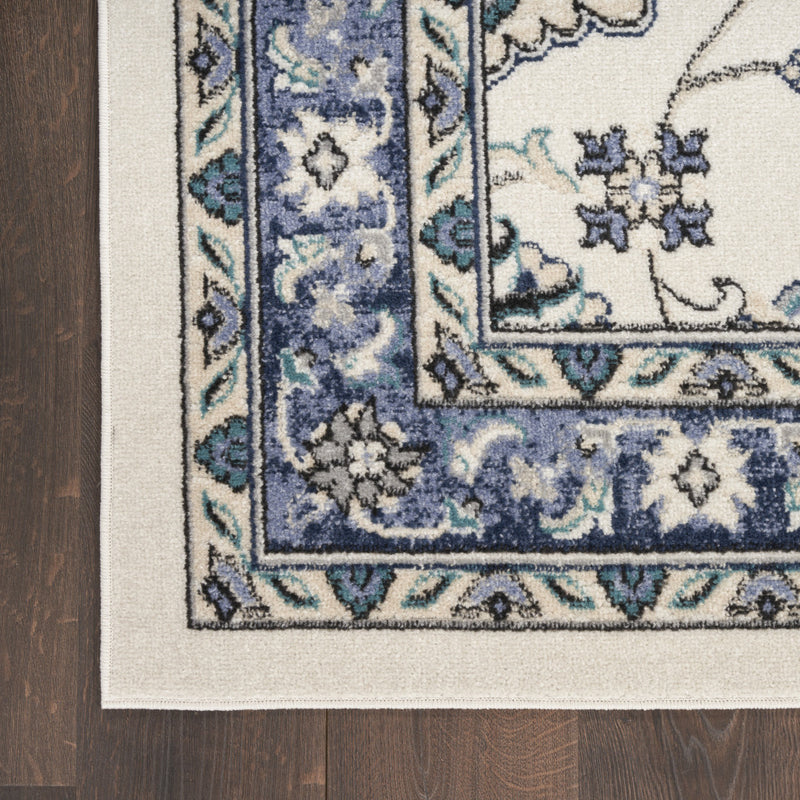 Corner view of ivory and blue floral rug with detailed border and flat edge