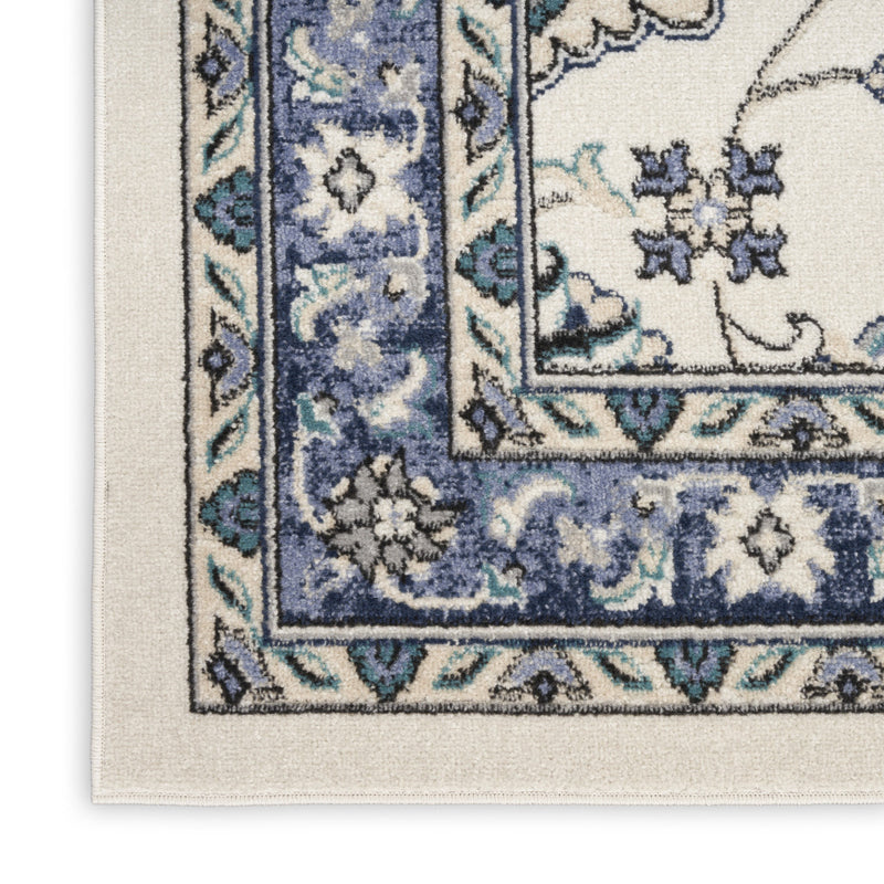 Flat-lay corner of ivory and blue floral area rug with patterned trim