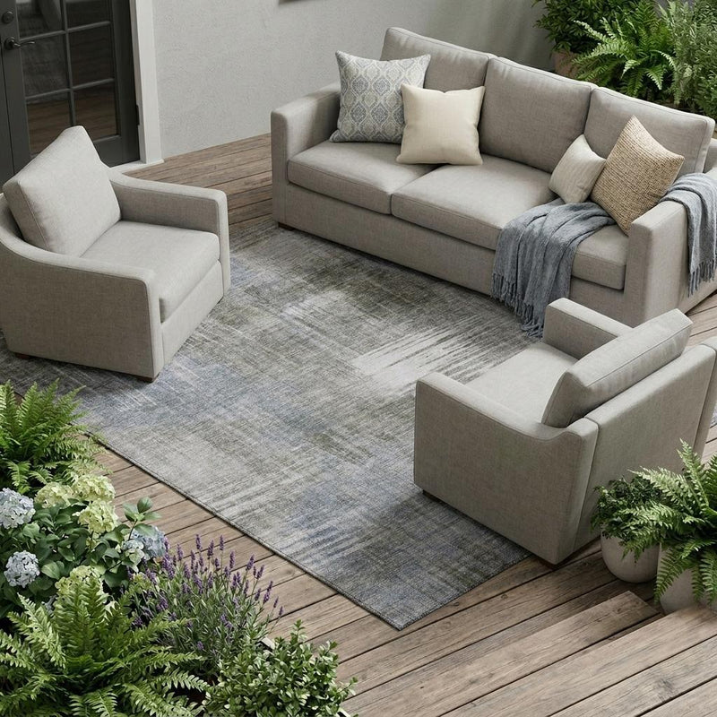 Large indoor area rug with abstract distressed pattern under modern outdoor sofa set.