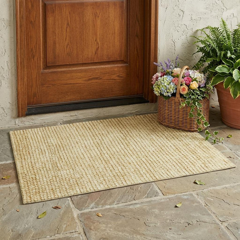 Wheat gold area rug with textured loop pile placed on stone floor at doorway
