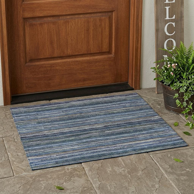 Blue and gray striped area rug on stone tile in front of a door