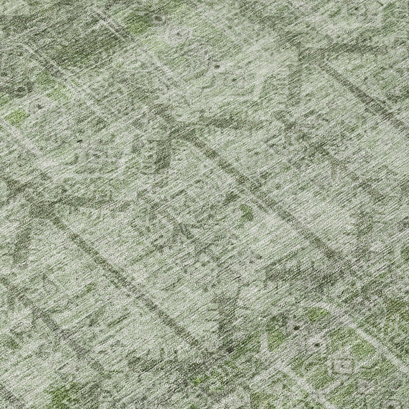 Sage green rug surface with faded tribal pattern and speckled textured finish
