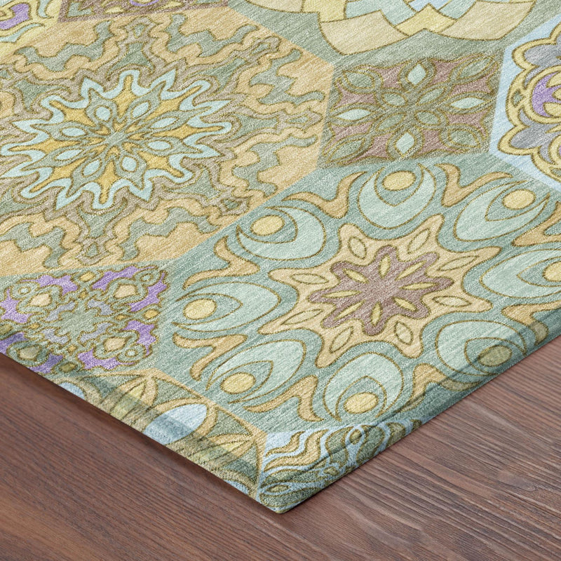 Close-up corner of gold and green patchwork area rug with ornate swirl floral design