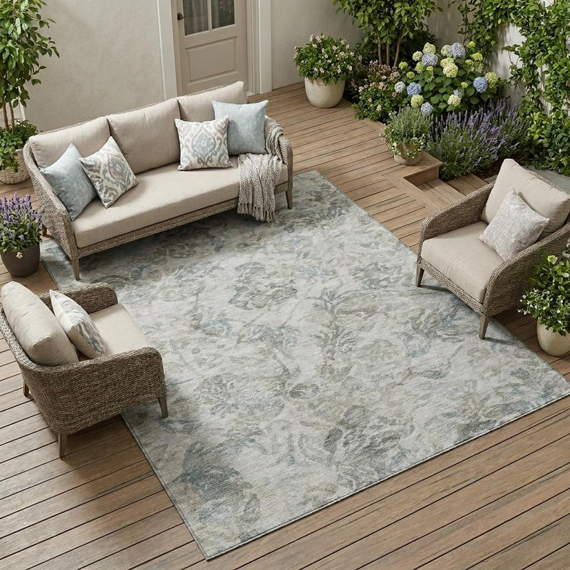 Indoor/outdoor area rug, light gray with faded teal floral pattern, on outdoor patio