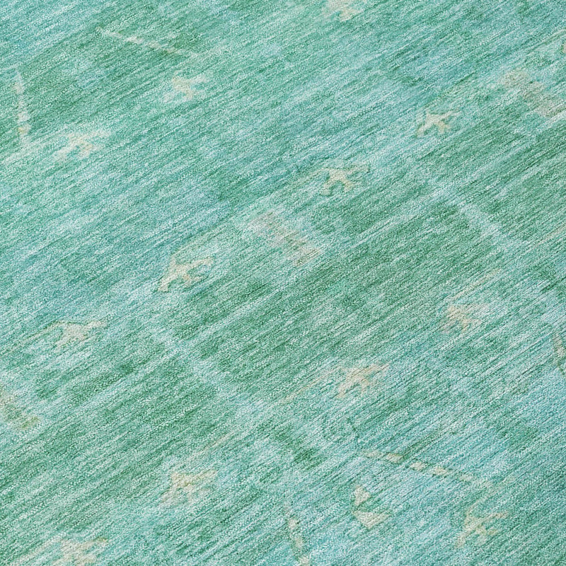 Close-up of teal-green rug surface with subtle tribal motifs and worn texture