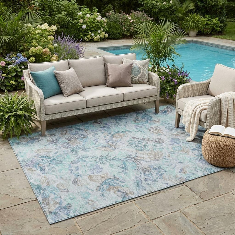 Indoor outdoor area rug in light blue with floral pattern laid on patio stones