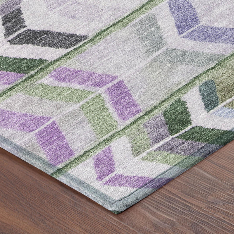 Bordered round area rug featuring light gray field with green, lavender, purple, and black motifs.