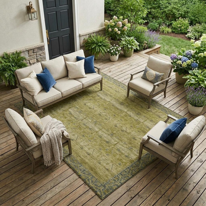 Green and olive outdoor area rug with faded blue tribal motif and border