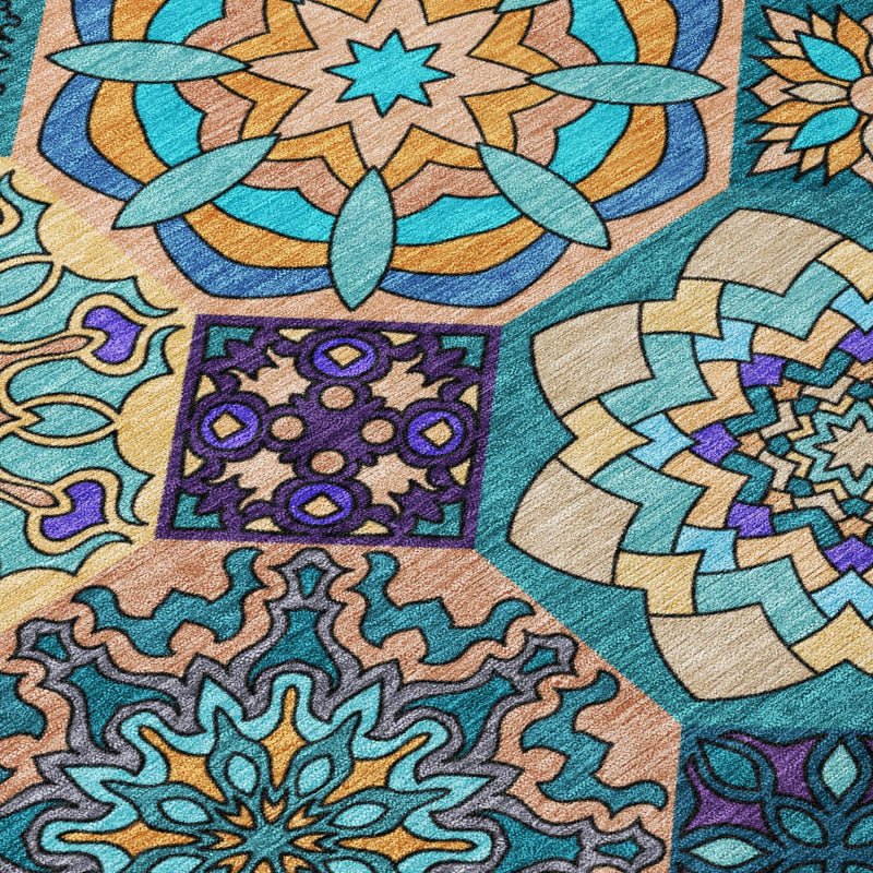 Area rug close-up showing teal, tan, purple, and gold ornamental stitched pattern