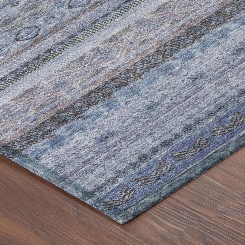Corner view of blue and lilac striped area rug on wood flooring