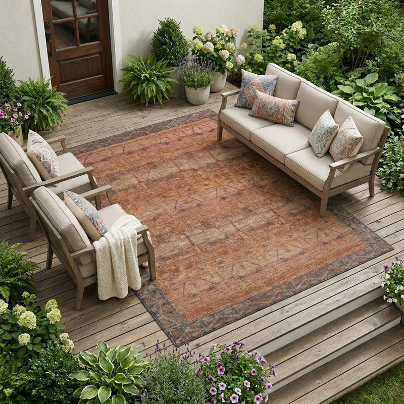 Outdoor area rug with rust-orange distressed tribal design and blue motifs.
