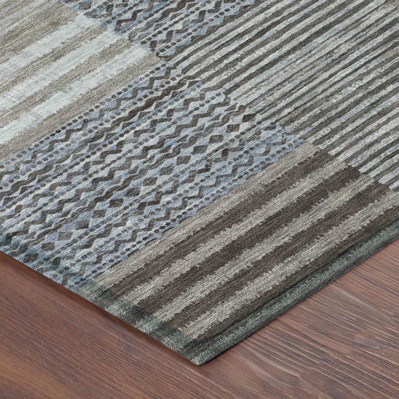 Close-up patchwork rug showing striped fibers in gray, beige, and brown with blue motifs