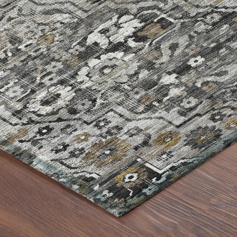 Corner view of gray and black medallion floral area rug with yellow accents