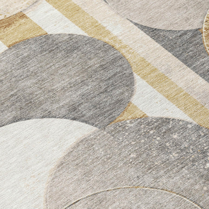 Close-up of geometric rug with gray, cream, and gold striped shapes and circles