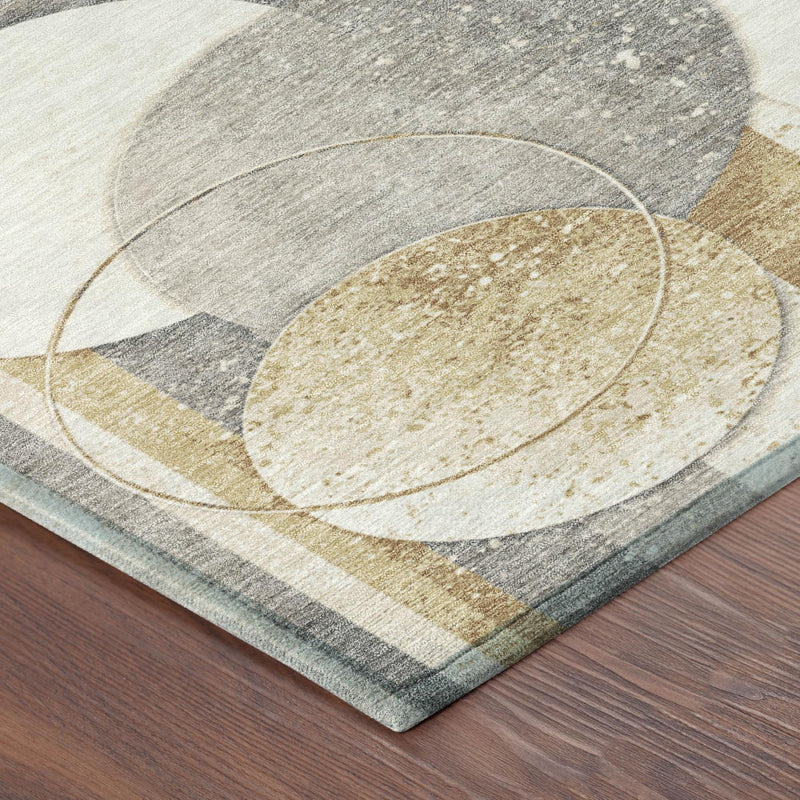 Corner of geometric rug with gray, cream, and gold textured oval and striped circles