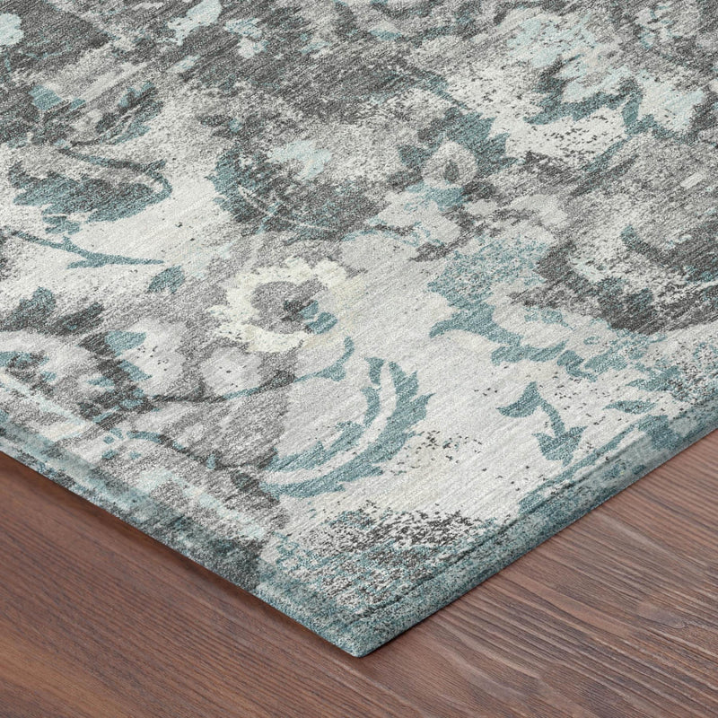 Corner detail of a silver, gray, and light blue distressed floral area rug
