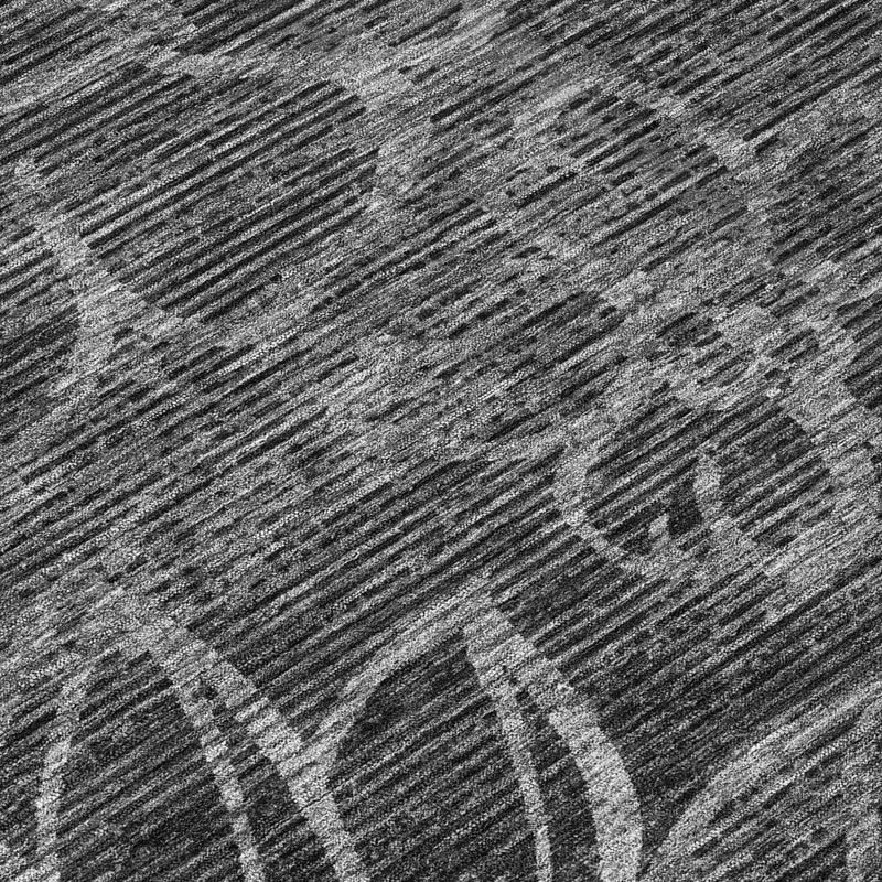 Close-up area rug texture with dark graphite pattern and light floral outlines.