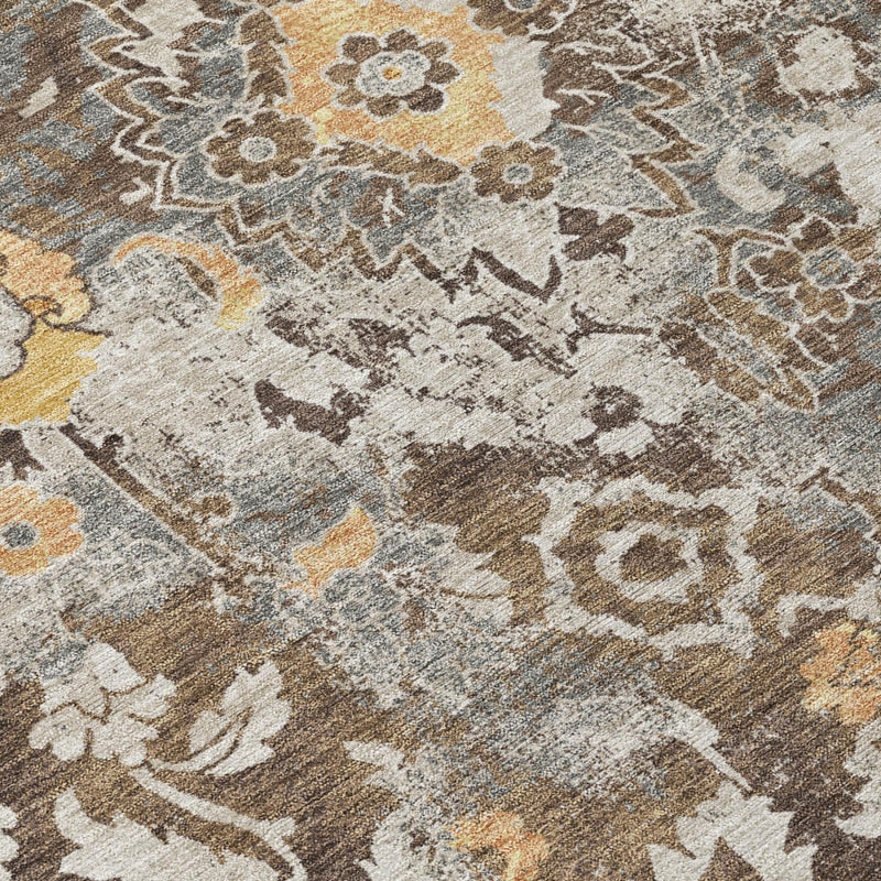 Close-up of distressed floral rug pile in brown, beige, and blue-gray with mustard