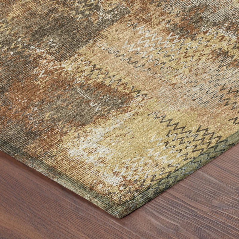 Corner of abstract area rug with copper, orange, beige and gray distressed mottling