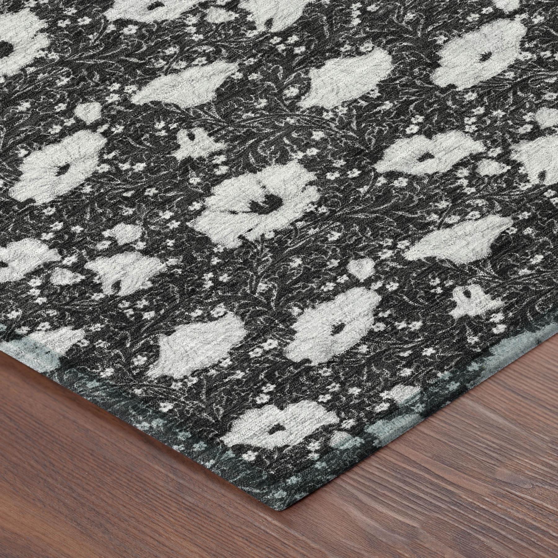 Corner view of floral area rug, black base with light gray medallion pattern and flat edge