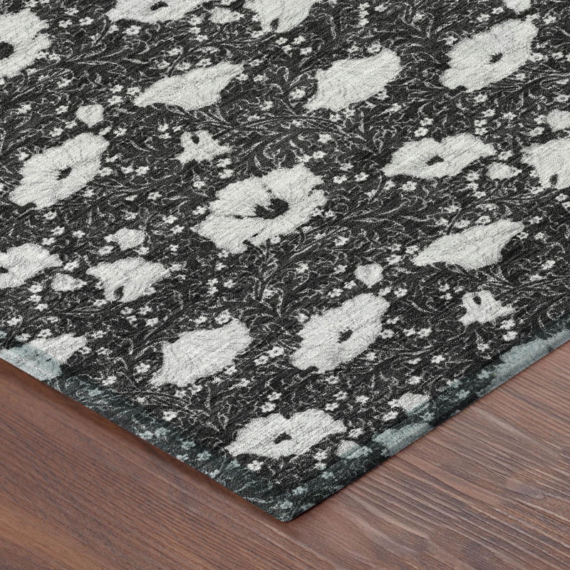 Corner view of floral area rug, black base with light gray medallion pattern and flat edge