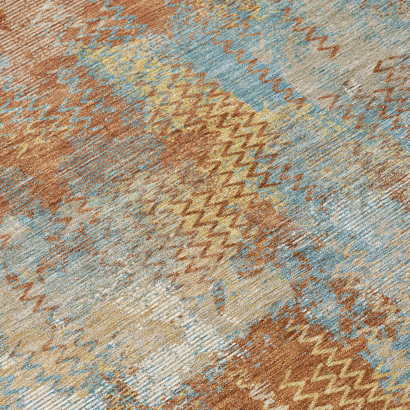 Close-up of round abstract rug texture with rust-brown and light-blue zigzag stripes.