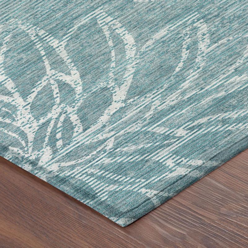 Corner detail of teal-blue area rug with distressed white floral motif