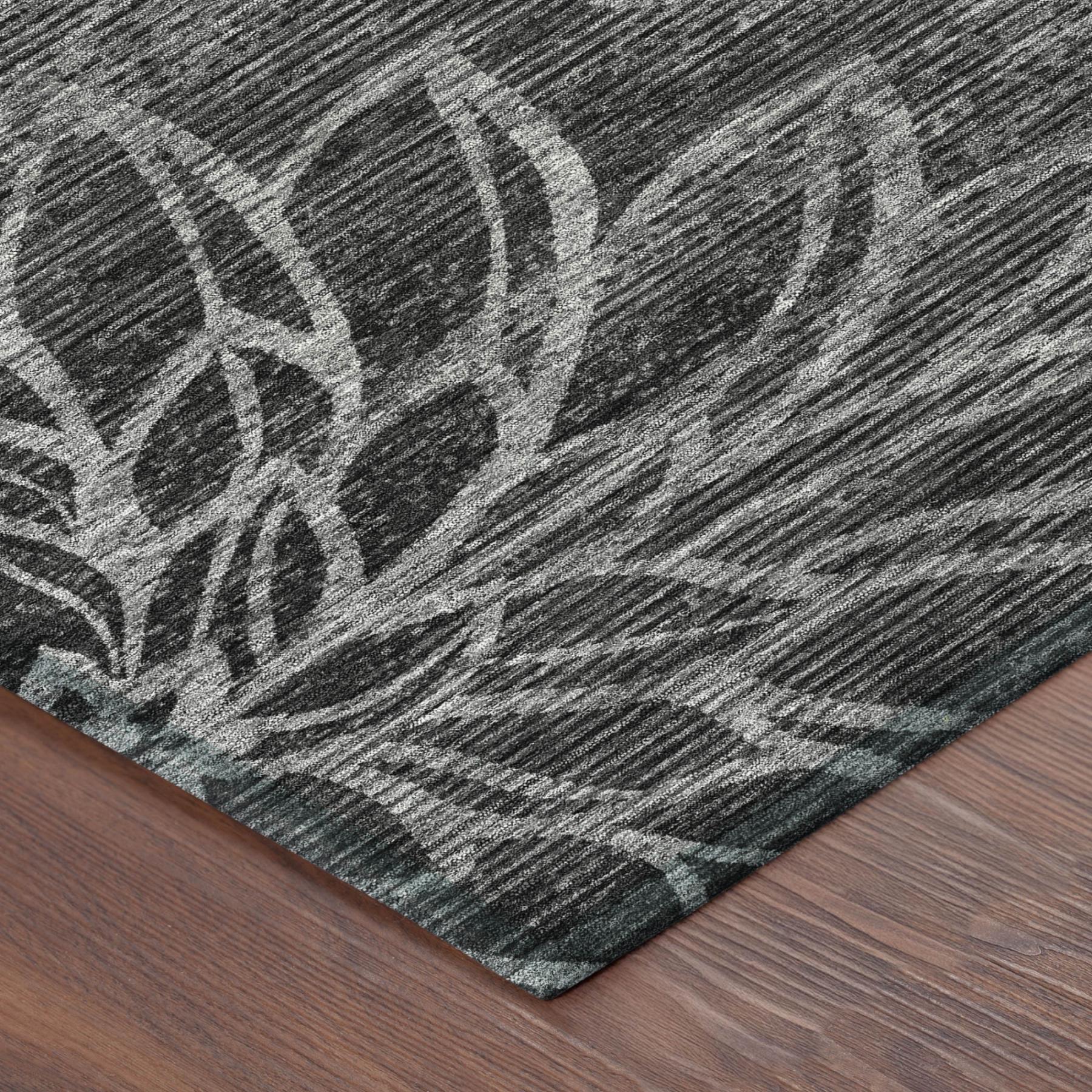 Corner of graphite rug showing stitched border and faded white floral motif
