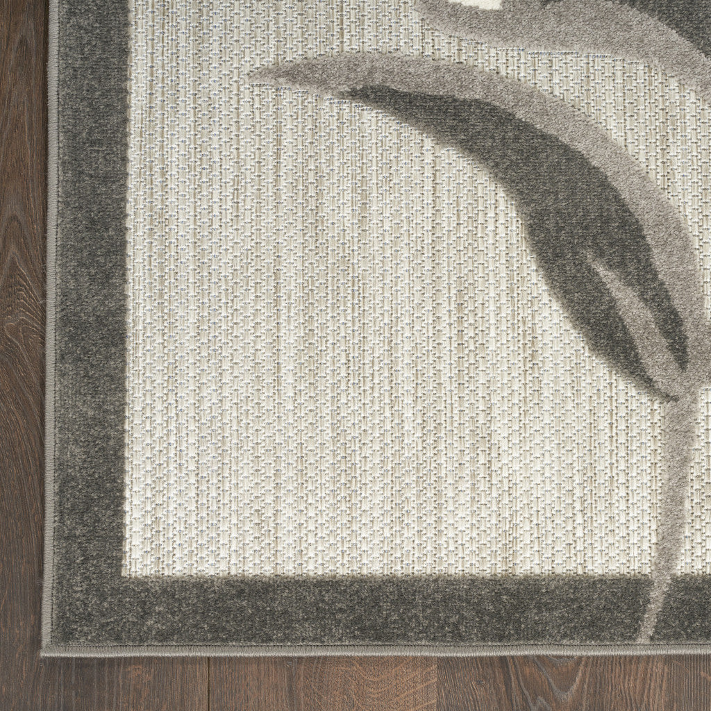 Corner view of beige area rug with gray floral border and textured surface