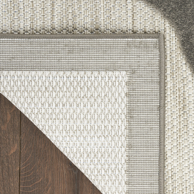 Beige textured area rug corner with dark binding and woven pattern
